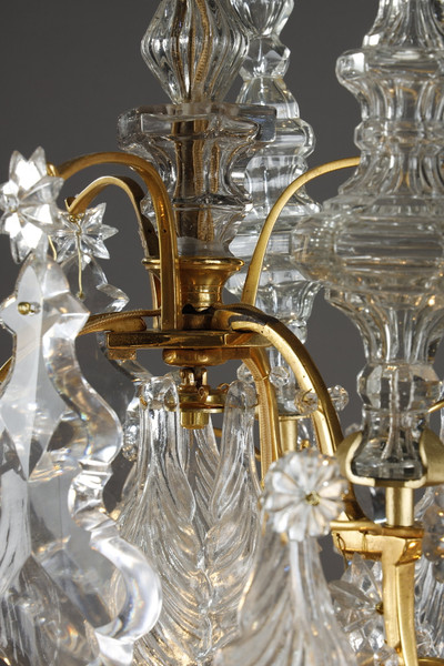 Una lámpara de araña de seis luces en bronce dorado, adornada con colgantes y dagas de cristal tallado