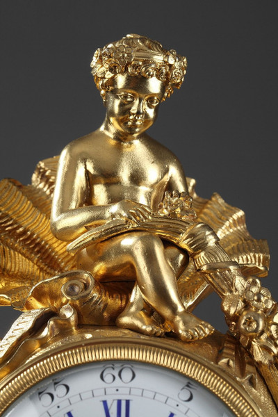 PENDULE DE STYLE ROCAILLE EN BRONZE DORE ORNEE D'UN AMOUR DANS UNE COQUILLE