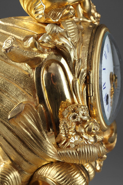 PENDULE DE STYLE ROCAILLE EN BRONZE DORE ORNEE D'UN AMOUR DANS UNE COQUILLE