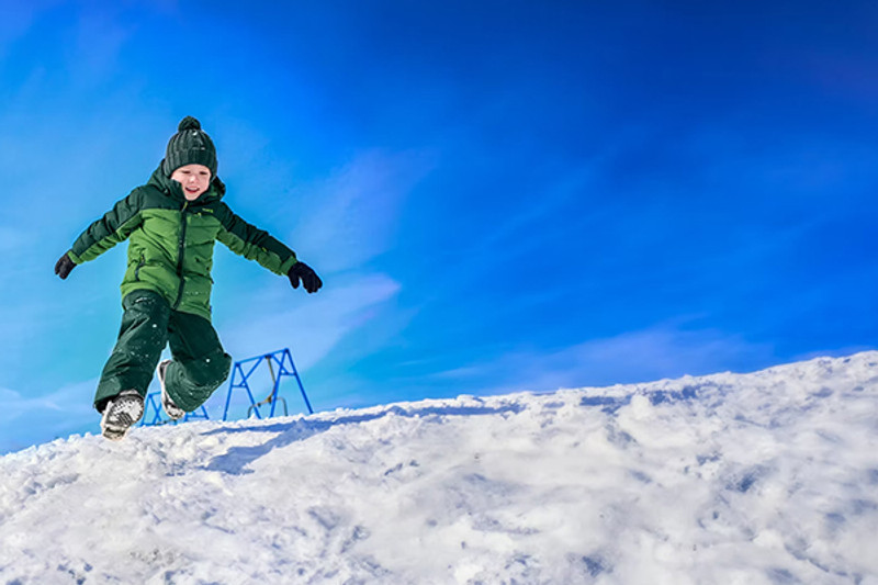 Boy sitting in snow wearing jacket and pants