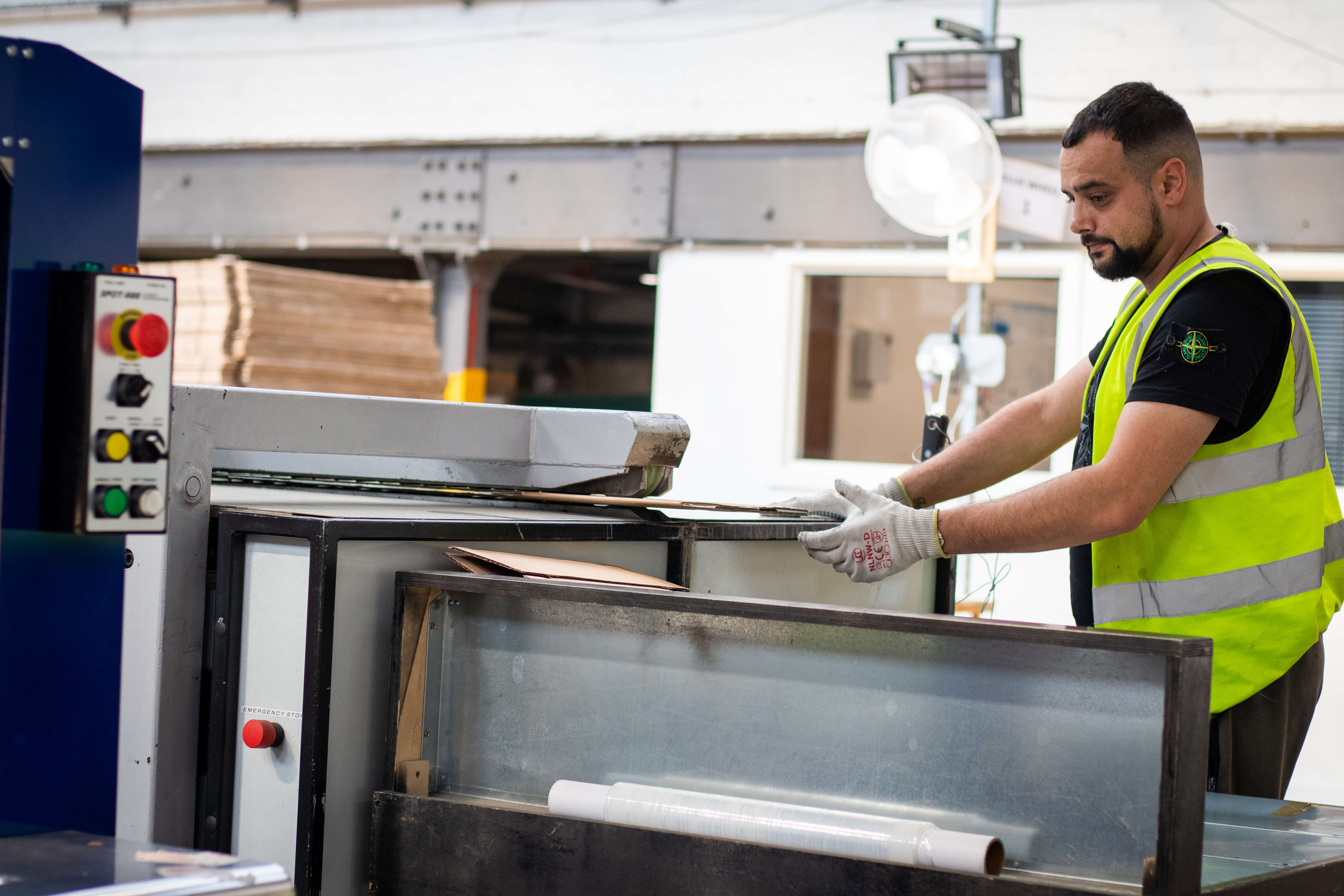 Man with beard in high vis preparing boxes at a machine
