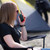 Woman sitting in a camping chair using a Motorola Talkabout T210 two-way radio at a campsite.