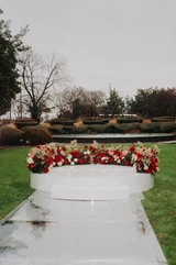 A close-up of an elevated wedding ceremony decorated with deep red, mauve, and ivory floral meadows placed in a semi-circle.