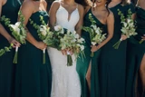 Bridal party wearing emerald green dresses hold modern flower arrangements with callas lilies. 