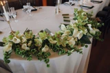 Eight classic green and white bridesmaid bouquets with a modern design are placed next to each other on the edge of a table.