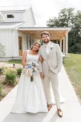 A bride holding a multi-color pastel floral bridal bouquet poses wit a groom.
