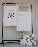 Wedding seating chart display with white floral arrangements and modern black-and-white signage.