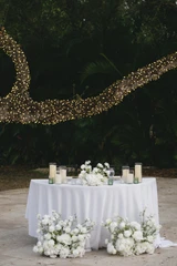 White florals decorate a sweetheart table at a wedding reception.