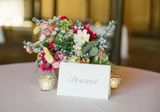 Elegant wedding table décor with pastel floral centerpieces, candles, and gold accents arranged for a reception.