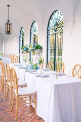 Blue and white floral centerpiece with hydrangeas, roses, and greenery arranged on a reception table.