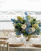 Large Centerpiece on a dining table made with blue white and green hydrangea in front of a lake