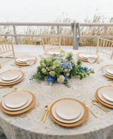 Dining table with plates and silverware with a blue and white hydrangea floral arrangement in the middle