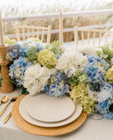Blue white and green hydrangeas on a table with a place setting
