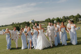 A bridal party walking towards the camera holding blue and white florals