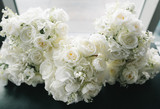 Floral bouquets of white roses, ranunculus, hydrangeas, and lily of the valley lined up 