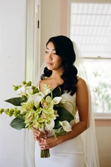 Bride holding a white and green floral arrangement contains callas lilies and greenery. 