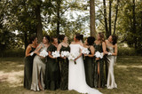 Bride and her bridesmaids in green dresses holding white floral bouquets