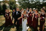 Bridal party walking while holding red and white flowers