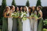 A bride and her bridesmaids wearing shades of green while holding green and white floral bouquets with a modern design.