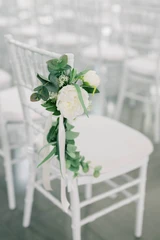 A white floral and greenery aisle marker sits on the side of the chair for minimal decoration.