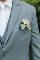 A close-up shot of a groom's pocket boutonniere featuring an assortment of wildflowers.