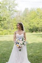 A bride poses for a photo as she looks down at her multi-color pastel floral bridal bouquet.