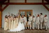 Bridesmaid wearing butter yellow and groomsmen wearing light tan suits surround the bride and groom as they share a kiss.