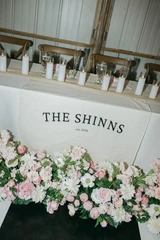 Light pink and ivory floral meadows line the front of a sweetheart table at a wedding reception.