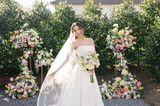 Bride by a cake table filled with Lucy Collection flowers