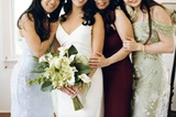 A bride holding a modern green and white bridal bouquet and her bridesmaid wearing different colored dresses pose for a photo.