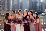 Bride and her bridesmaids in purple dresses holding purple flowers