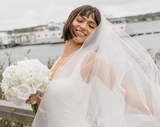 Bride holding a white rose bouquet in front of a marina