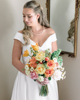 Bride holding bouquet of brightly colored floral bouquet with orange, yellow, and pink flowers