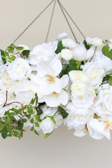 Close-up of a floral chandelier made of white roses, ranunculus, and orchids, accented with wisteria greenery