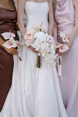 Bride holding a cascading orchid bouquet flanked by bridesmaids carrying coordinating blush anthurium bouquets.