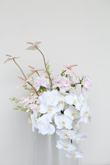 Large vaseless arrangement with blush anthuriums, white orchids, ivory roses, pale pink roses, and orchid sprays.