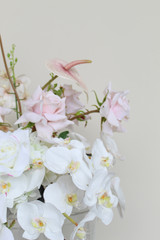 Close-up of large vaseless arrangement with blush anthuriums, white orchids, ivory roses, pale pink roses, and orchid sprays.