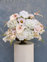 Grand centerpiece featuring white hydrangeas, white roses, blush roses, blush anthuriums, and cascading orchids in a gold compote vase.