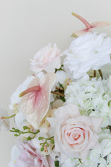 Close-up of a grand centerpiece featuring white hydrangeas, white roses, blush roses, blush anthuriums, and cascading orchids in a gold compote vase.