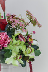 Floral Meadow featuring deep burgundy calla lilies, white calla lilies, blush peonies, pale green hydrangeas, green cymbidium orchids, burgundy roses, white anthuriums, cascading burgundy amaranthus, and airy pink accent blooms.
