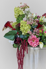 Floral Meadow featuring deep burgundy calla lilies, white calla lilies, blush peonies, pale green hydrangeas, green cymbidium orchids, burgundy roses, white anthuriums, cascading burgundy amaranthus, and airy pink accent blooms.