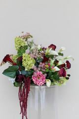 Floral Meadow featuring deep burgundy calla lilies, white calla lilies, blush peonies, pale green hydrangeas, green cymbidium orchids, burgundy roses, white anthuriums, cascading burgundy amaranthus, and airy pink accent blooms.