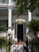 Entrance to a house with a white floral chandelier suspended from the top balcony