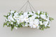 A floral chandelier made of white roses, ranunculus, and orchids, accented with wisteria greenery, suspended from the ceiling
