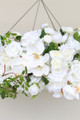 Close-up of a floral chandelier made of white roses, ranunculus, and orchids, accented with wisteria greenery