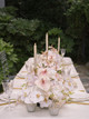 Wedding reception table centerpiece featuring blush anthuriums, white orchids, pale roses, and candle accents arranged along a long banquet table.