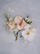 Blush anthurium, white and peach orchids, and white roses arranged on a light grey background