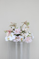 Low floral centerpiece with blush anthuriums, white orchids, pale pink roses, and delicate orchid sprays designed for wedding décor.