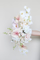Floral arrangement featuring blush anthuriums, white orchids, ivory roses, hydrangeas, and cascading floral accents.