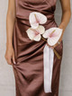 Bridesmaid holding the Blush Anthurium Petite Bouquet featuring three blush pink anthuriums with flowing ivory ribbon against a brown satin dress.
